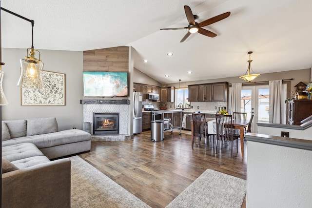 living room with a tiled fireplace, recessed lighting, dark wood finished floors, ceiling fan, and lofted ceiling