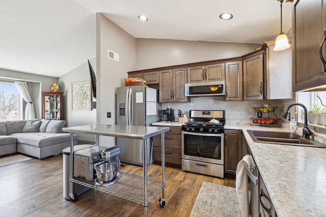 kitchen with decorative backsplash, a sink, appliances with stainless steel finishes, visible vents, and open floor plan