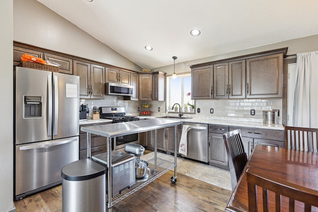 kitchen with dark wood finished floors, appliances with stainless steel finishes, lofted ceiling, and decorative backsplash