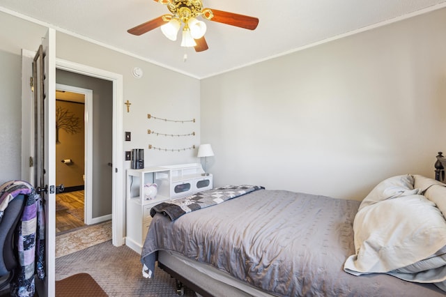 carpeted bedroom with crown molding, a ceiling fan, and baseboards