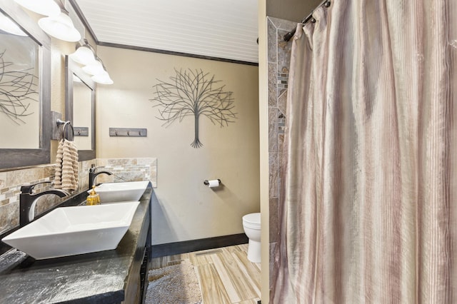bathroom with toilet, double vanity, a sink, and wood finished floors
