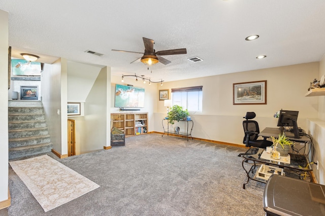 carpeted home office featuring baseboards, visible vents, a ceiling fan, and a textured ceiling