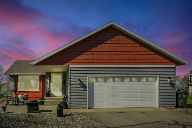 view of front of house featuring roof with shingles, aphalt driveway, entry steps, and a garage