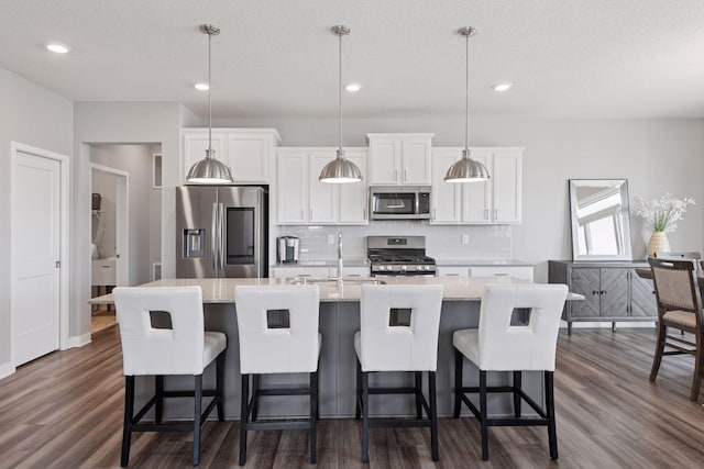 kitchen with backsplash, white cabinetry, dark wood-type flooring, and stainless steel appliances