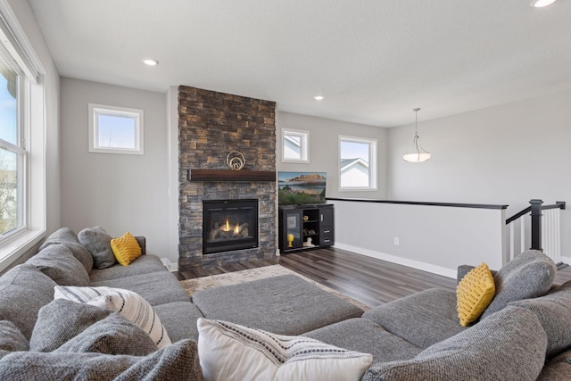 living area with baseboards, a fireplace, wood finished floors, and a wealth of natural light