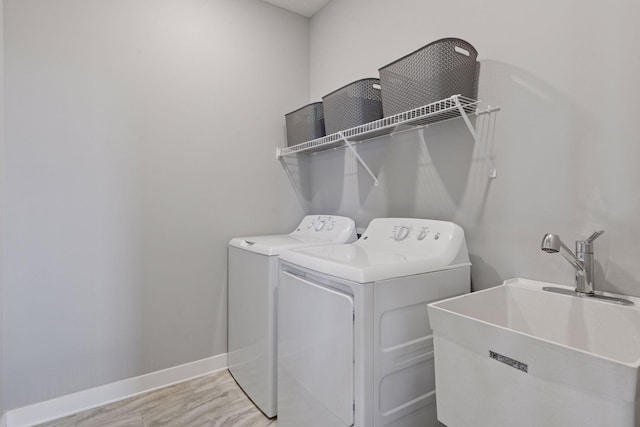 washroom featuring laundry area, a sink, independent washer and dryer, baseboards, and light wood-style flooring