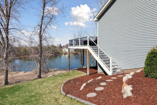 view of property exterior featuring a yard, a deck with water view, and stairs