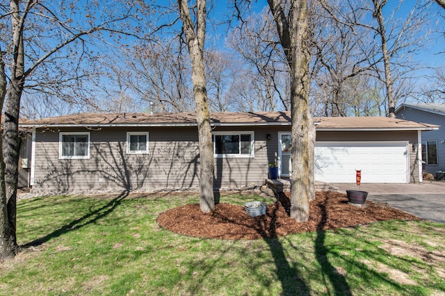 view of front of house featuring an attached garage, a front lawn, and aphalt driveway