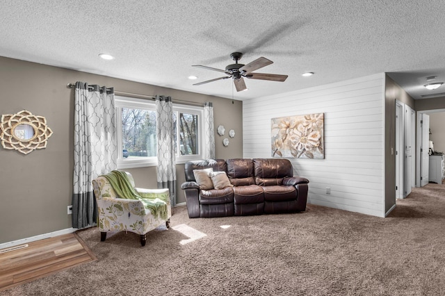 carpeted living area with recessed lighting, a ceiling fan, a textured ceiling, and wooden walls