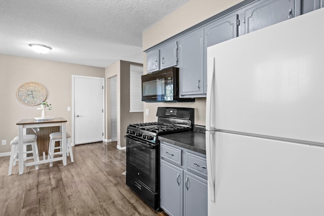 kitchen featuring a textured ceiling, dark countertops, gray cabinetry, and black appliances