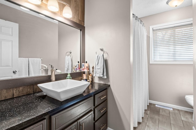 bathroom featuring visible vents, vanity, baseboards, toilet, and a shower with shower curtain