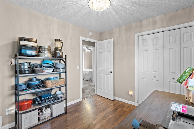 home office with baseboards, a textured ceiling, wood finished floors, and a notable chandelier