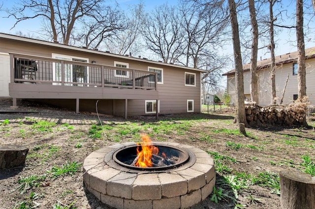 back of property featuring a fire pit, fence, and a deck