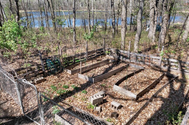 view of yard with fence, a water view, and a vegetable garden