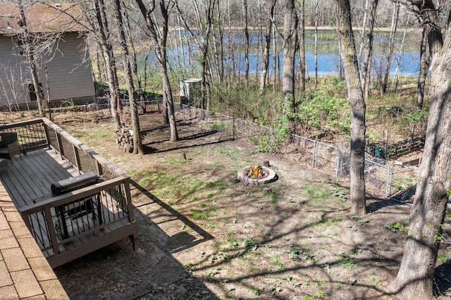 view of yard featuring an outdoor fire pit, fence, and a deck with water view