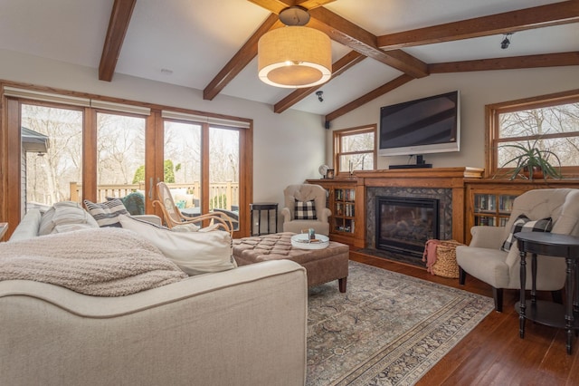 living area with a premium fireplace, vaulted ceiling with beams, and wood finished floors