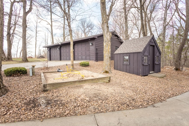 view of side of property with board and batten siding, an outbuilding, roof with shingles, and a garage
