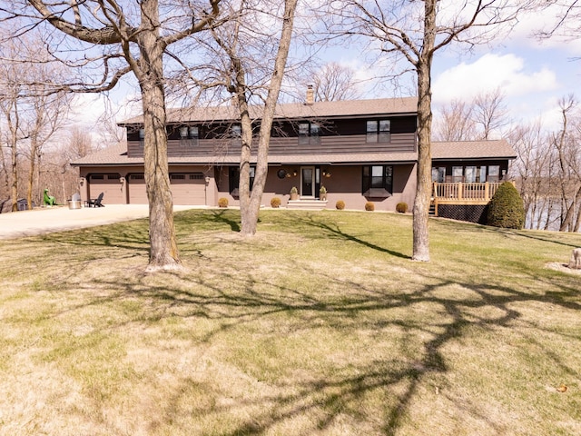 view of front facade featuring concrete driveway, a chimney, an attached garage, a front yard, and roof with shingles