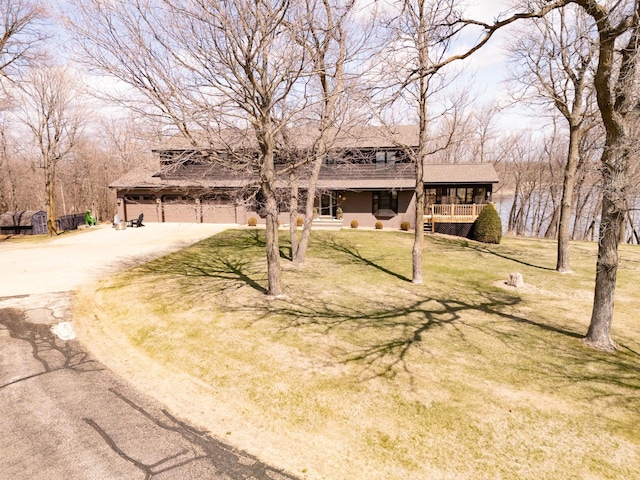 view of front of house with driveway, a porch, a front lawn, and roof with shingles