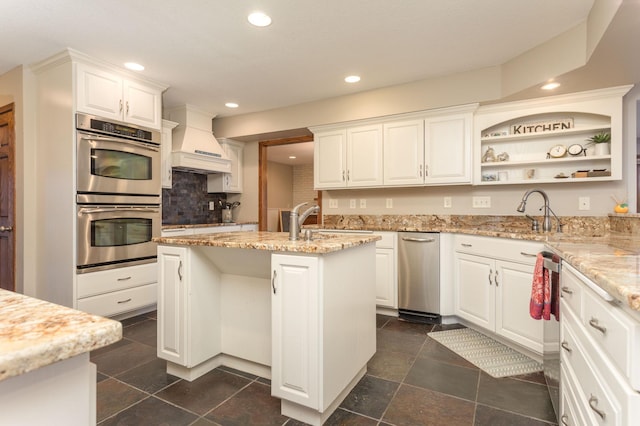 kitchen with appliances with stainless steel finishes, a sink, and white cabinetry