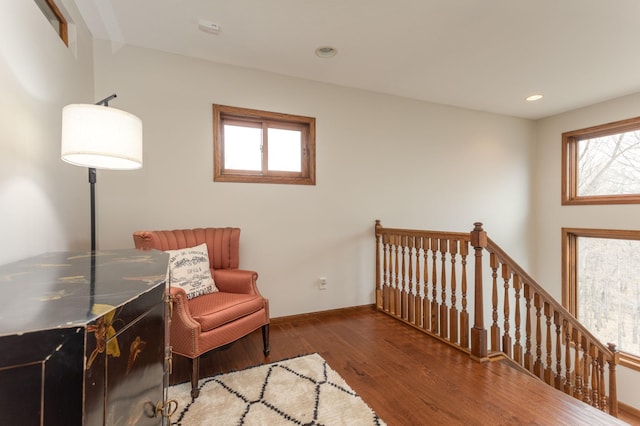 living area with plenty of natural light, baseboards, wood finished floors, and an upstairs landing
