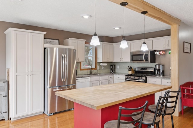 14921 Zeolite St NW, Ramsey, MN 55303 - kitchen featuring a breakfast bar area, wood counters, appliances with stainless steel finishes, white cabinetry, and light wood-style floors