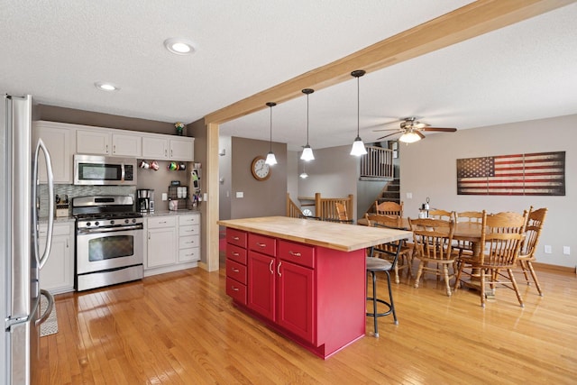 14921 Zeolite St NW, Ramsey, MN 55303 - kitchen with wooden counters, stainless steel appliances, a kitchen breakfast bar, white cabinets, and light wood-type flooring