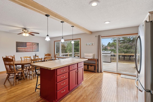 14921 Zeolite St NW, Ramsey, MN 55303 - kitchen featuring light wood finished floors, freestanding refrigerator, a kitchen breakfast bar, a textured ceiling, and butcher block counters