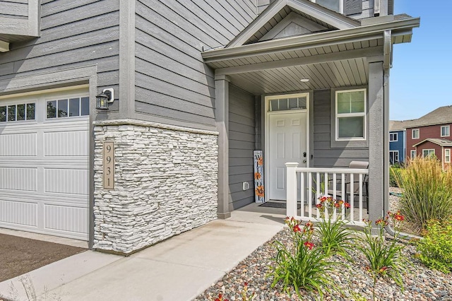 entrance to property with stone siding, covered porch, and a garage