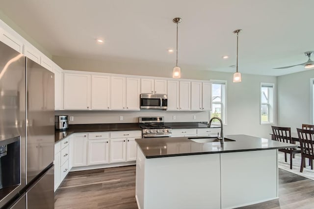 kitchen featuring dark countertops, dark wood-style flooring, stainless steel appliances, and a sink