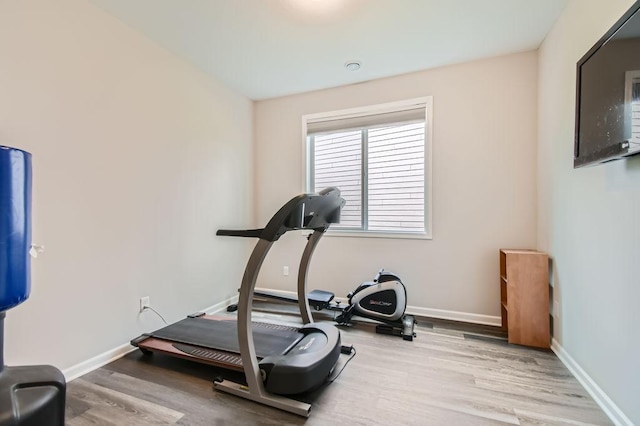 exercise room with baseboards and wood finished floors