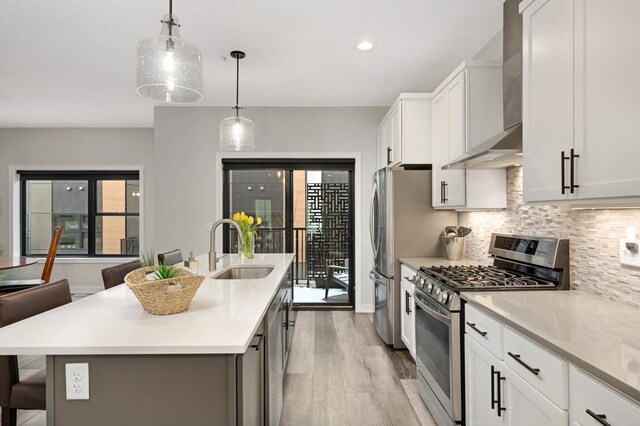 6369 16th Ave S, Richfield, MN 55423 - kitchen with appliances with stainless steel finishes, wall chimney range hood, an island with sink, backsplash, and light countertops