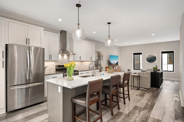 6369 16th Ave S, Richfield, MN 55423 - kitchen with appliances with stainless steel finishes, wall chimney range hood, tasteful backsplash, light wood-type flooring, and a kitchen bar