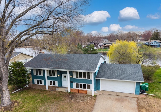 bi-level home featuring driveway, a shingled roof, a front lawn, and a garage