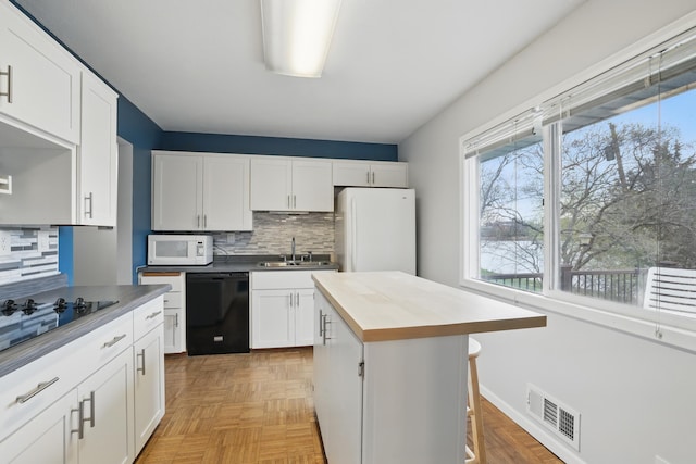 kitchen featuring visible vents, tasteful backsplash, a sink, white cabinets, and black appliances