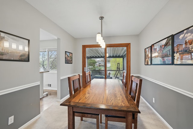dining space featuring light colored carpet, baseboards, visible vents, and an inviting chandelier