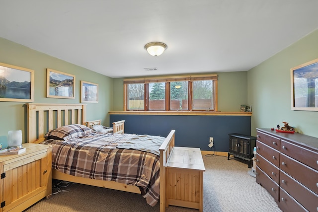 bedroom featuring visible vents, light colored carpet, and a wood stove