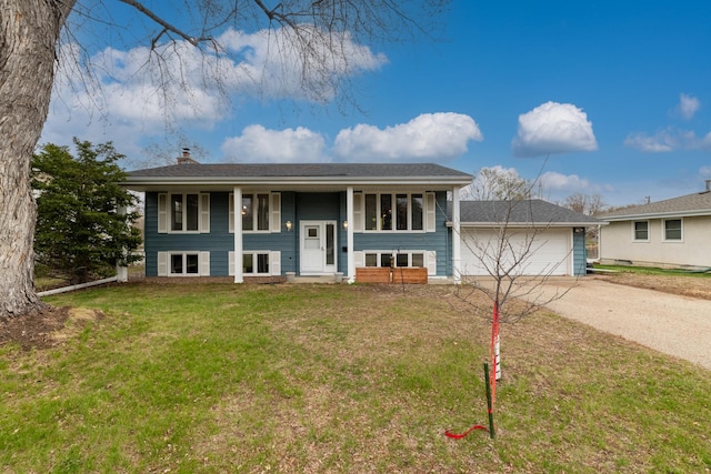 raised ranch with covered porch, driveway, a chimney, a garage, and a front lawn