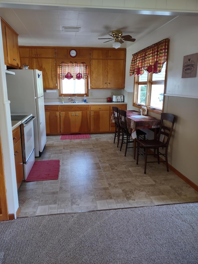 522 6th Ave, Madison, MN 56256 - kitchen with white range with electric stovetop, light countertops, brown cabinetry, a sink, and a ceiling fan