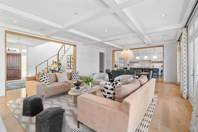 living room featuring stairs, light wood-style floors, a chandelier, coffered ceiling, and beamed ceiling