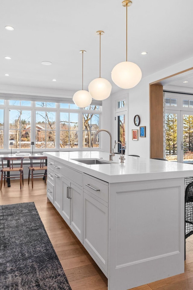 kitchen with a sink, healthy amount of natural light, an island with sink, white cabinets, and recessed lighting