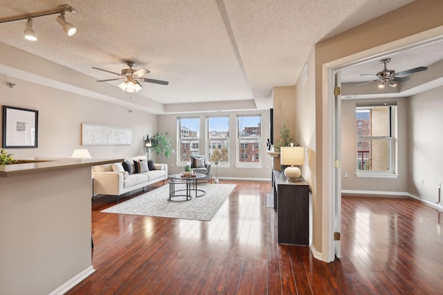 living area with plenty of natural light, dark wood-style flooring, and ceiling fan