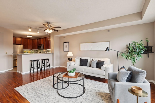 living room with baseboards, ceiling fan, and dark wood finished floors