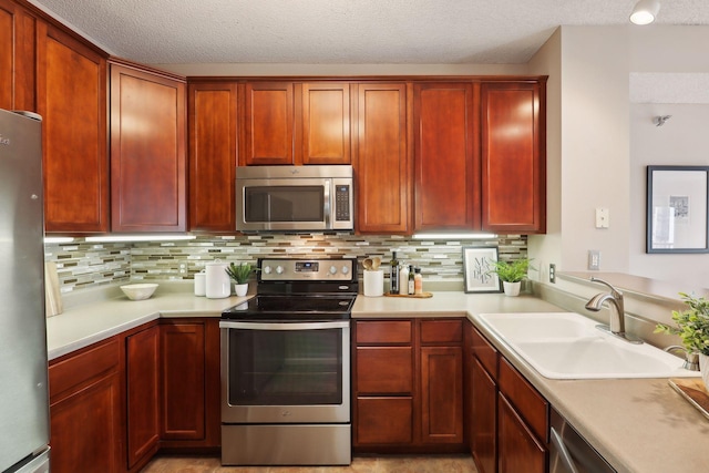 kitchen with stainless steel appliances, light countertops, reddish brown cabinets, a sink, and decorative backsplash