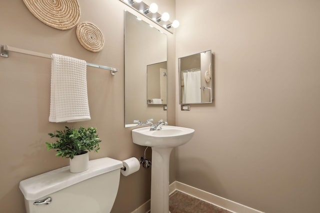 full bathroom featuring toilet, baseboards, and a sink