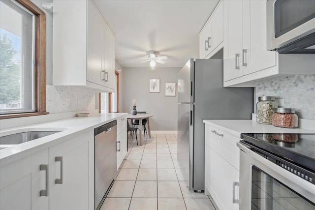 kitchen with stainless steel appliances, ceiling fan, light countertops, light tile patterned flooring, and white cabinetry