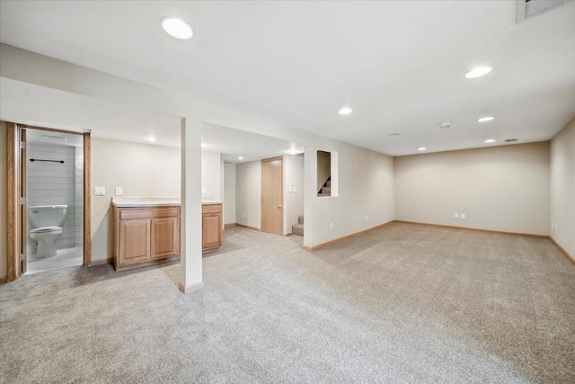 finished below grade area featuring light carpet, baseboards, recessed lighting, and stairs