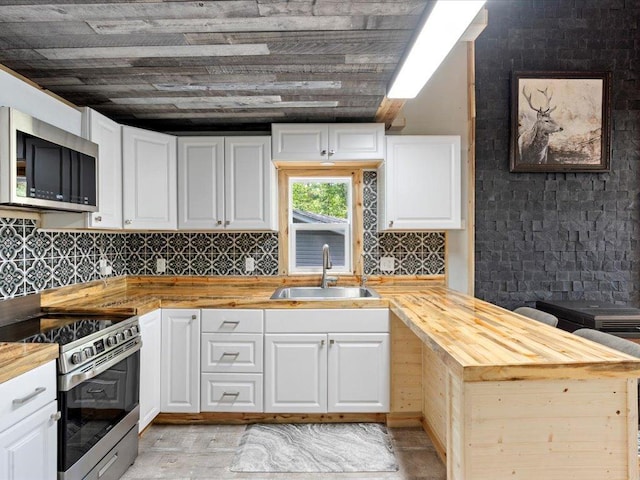 6274 Azalea Rd, Motley Twp, MN 56466 - kitchen featuring appliances with stainless steel finishes, a sink, butcher block counters, a peninsula, and white cabinets