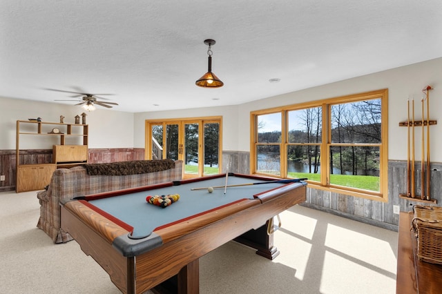 rec room with light carpet, ceiling fan, a water view, a wainscoted wall, and billiards