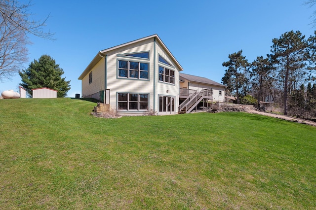 back of property featuring a yard, a deck, and stairs